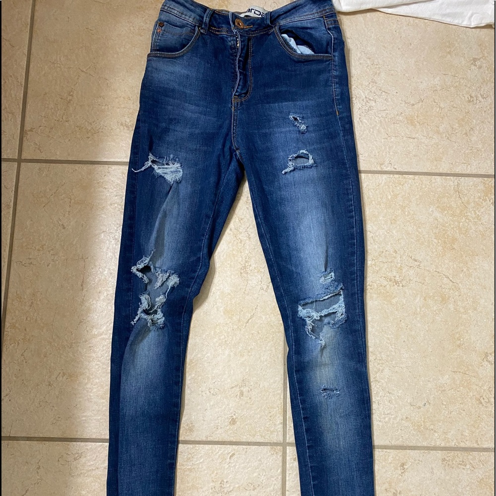 ripped blue jeans with fringe on bottom legs